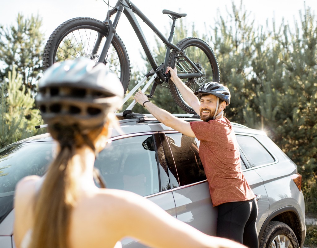 man putting bike on top of car