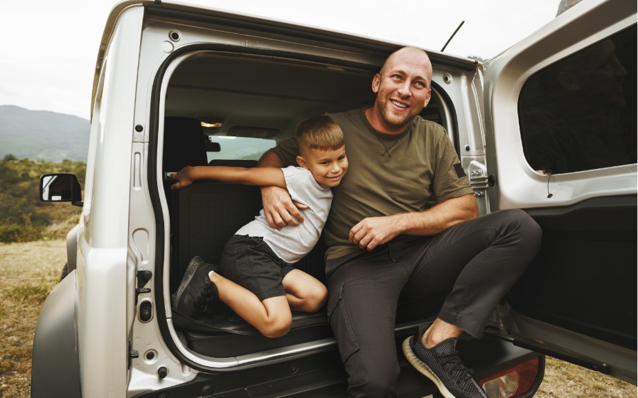 happy father son sitting at back of vehicle